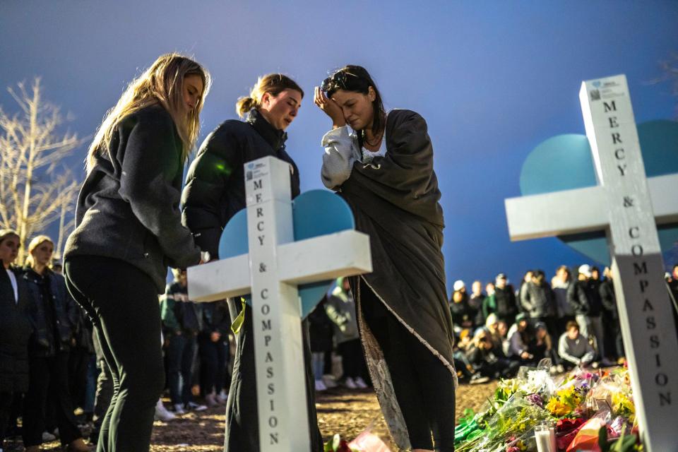 People sign a heart on a cross in memory of one of the people killed during a vigil at The Rock on the Michigan State University campus in East Lansing on Wednesday, February 15, 2023, to honor and remember the victims of the mass shooting that happened on the MSU campus that left three dead and multiple others injured. 