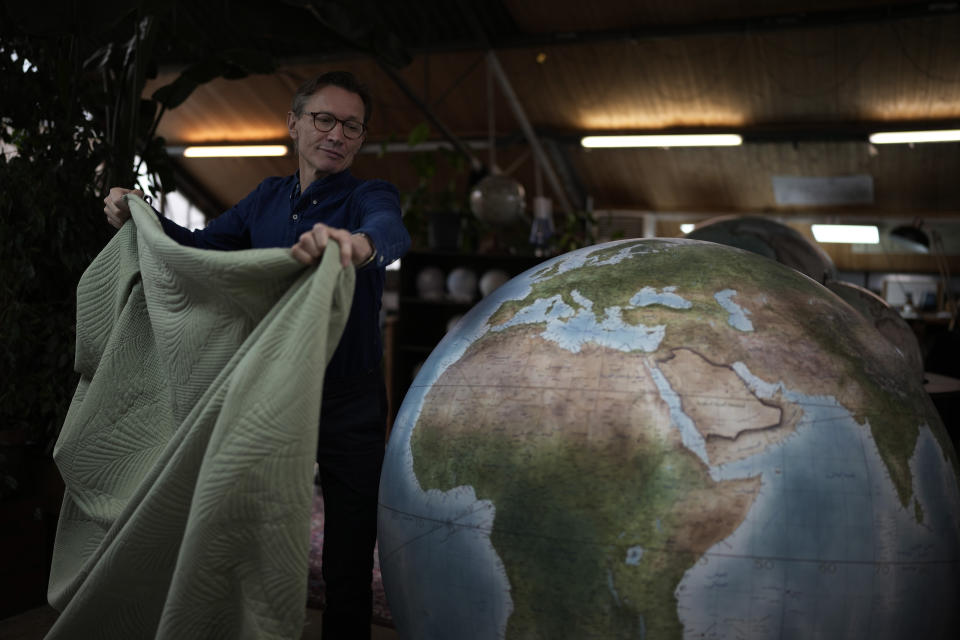 Peter Bellerby, the founder of Bellerby & Co. Globemakers, covers a globe at his studio in London, Tuesday, Feb. 27, 2024. Globes in the age of Google Earth capture the imagination and serve as snapshots of how the owners see the world and their place in it. Peter Bellerby made his first globe for his father, after he could not find one accurate or attractive enough. In 2008, he founded Bellerby & Co. Globemakers in London. His team of dozens of artists and cartographers has made thousands of bespoke globes up to 50 inches in diameter. The most ornate can cost six figures. (AP Photo/Kin Cheung)