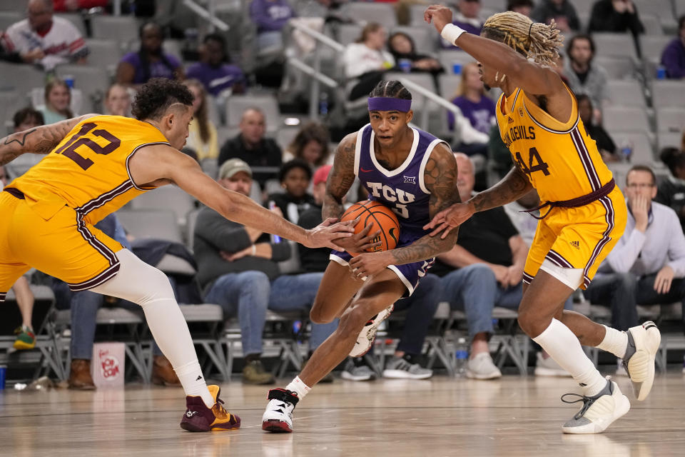 TCU guard Avery Anderson III secures the ball as he works through Arizona State's Jose Perez (12) and Adam Miller (44) during the first half of an NCAA college basketball game in Fort Worth, Texas, Saturday, Dec. 16, 2023. (AP Photo/Tony Gutierrez)