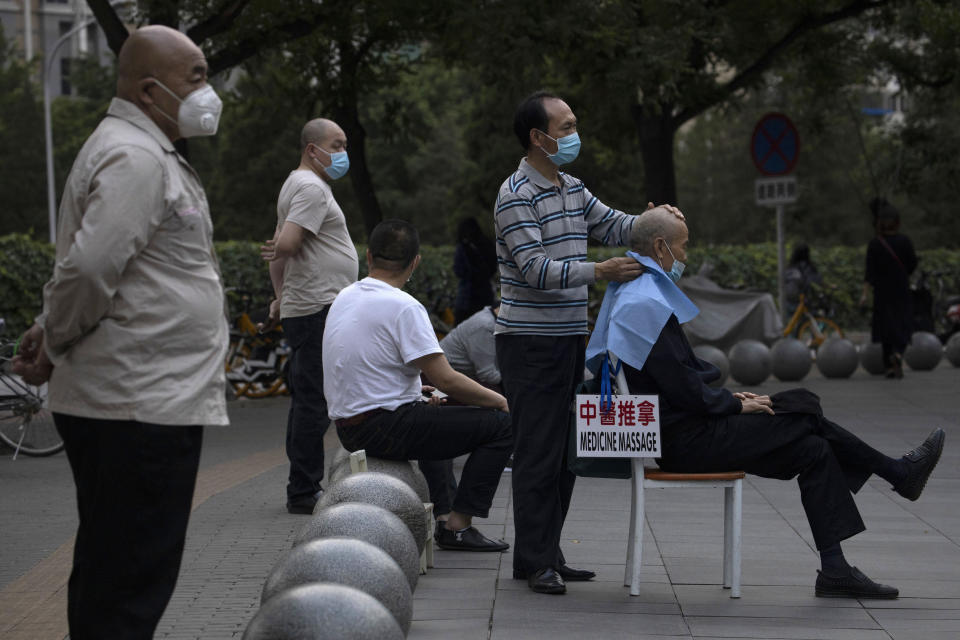 A masseur wearing a mask to curb the spread of the new coronavirus gives a customer a massage a shopping mall in Beijing on Monday, May 25, 2020. (AP Photo/Ng Han Guan)