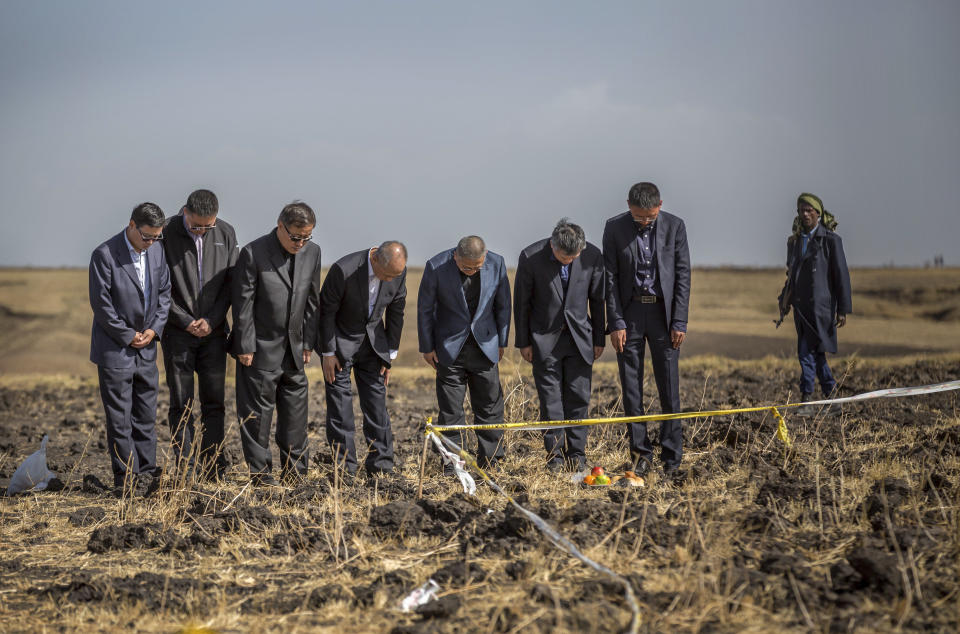 FILE - In this Tuesday, March 12, 2019 file photo, officials from the Aviation Industry Corporation of China (AVIC) pray next to an offering of fruit, bread rolls, and a plastic container of Ethiopian Injera, a fermented sourdough flatbread, placed next to incense sticks, at the scene where the Ethiopian Airlines Boeing 737 Max 8 crashed shortly after takeoff killing all 157 on board, near Bishoftu, or Debre Zeit, south of Addis Ababa, in Ethiopia. These African stories captured the world's attention in 2019 - and look to influence events on the continent in 2020. (AP Photo/Mulugeta Ayene, File)