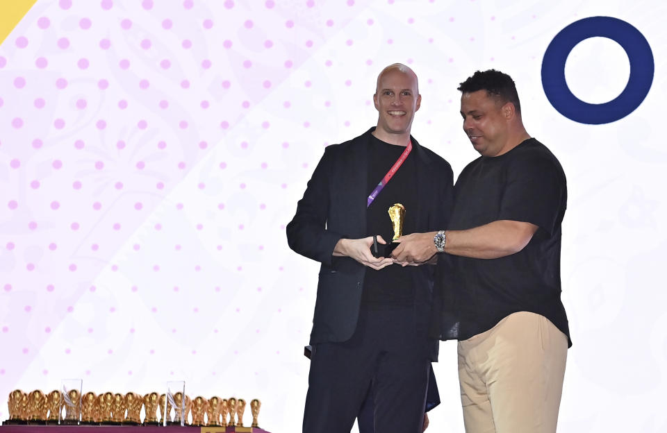 Grant Wahl smiles as he is awarded a World Cup replica trophy by soccer legend Ronaldo during an award ceremony in Doha, Qatar on Nov. 29, 2022. Wahl, one of the most well-known soccer writers in the United States, died early Saturday Dec. 10, 2022 while covering the World Cup match between Argentina and the Netherlands. (Brendan Moran, FIFA via AP)