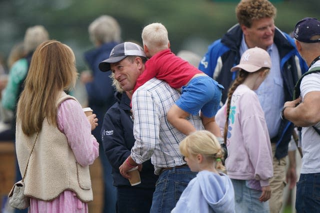 Lucas Tindall climbs on the back of his uncle, Peter Phillips, at the Defender Burghley Horse Trials at Burghley House near Stamford, Lincolnshire,