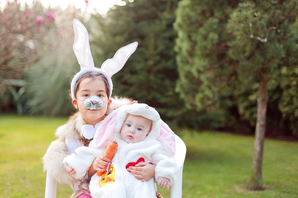 two siblings wearing easter bunny costumes outdoors