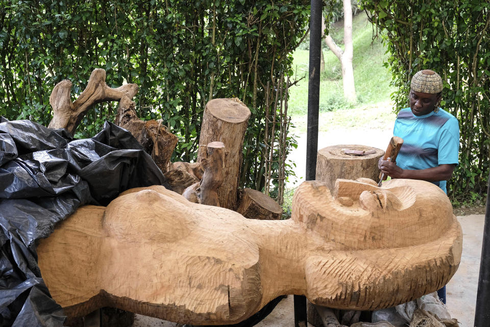 Lilian Nabulime carving wood into a wooden sculpture piece at her workshop in Kyanja, a suburb in Kampala City, Wednesday Nov. 29 2023.. Lilian Nabulime hasn't forgotten the time in the 1990s when the Ugandan capital had just one commercial art gallery, a small space that emerging artists struggled to get into. Now there are at least six in Kampala, including one whose curators recently exhibited the sculptor's contrarian work. (AP Photo/Hajarah Nalwadda.)