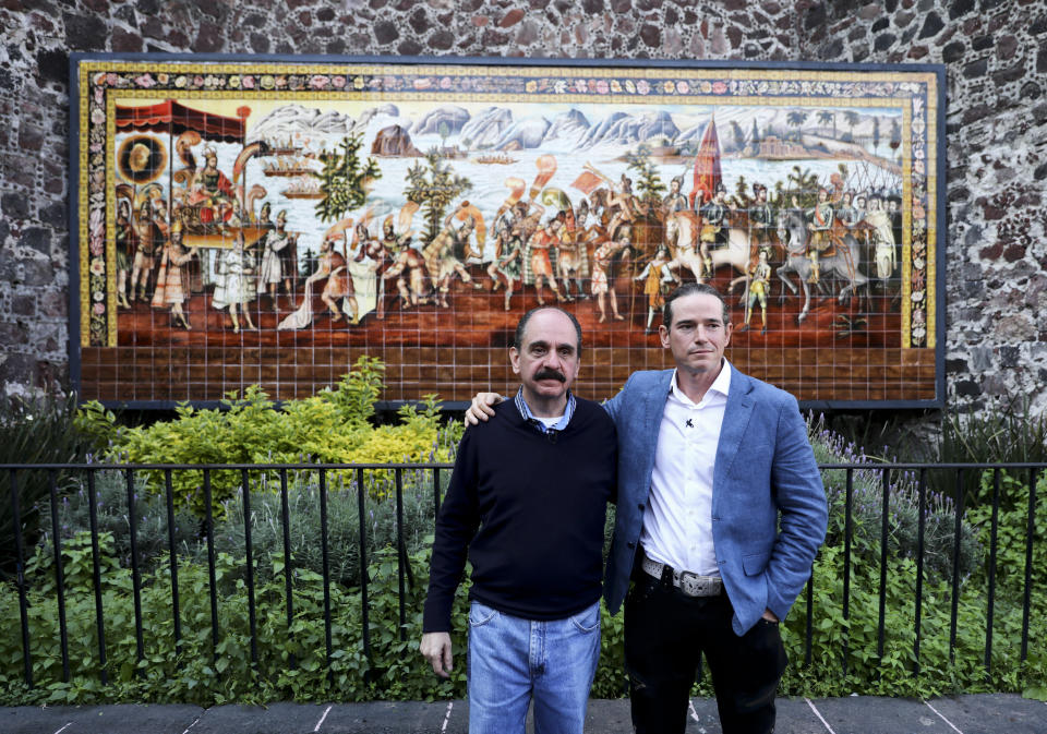 Federico Acosta, a Mexican who traces his lineage back 16 generations back to Moctezuma's daughter, left, and Italian Ascanio Pignatelli also of the 16th generation descended from Hernan Cortes' daughter, pose for a photo in front of a mural commemorating the meeting of the Spanish conquistador and the Aztec emperor, in Mexico City, Friday, Nov. 8, 2019. Descendants are meeting in Mexico City to mark the 500th anniversary of their forbearers' first encounter. (AP Photo/Eduardo Verdugo)