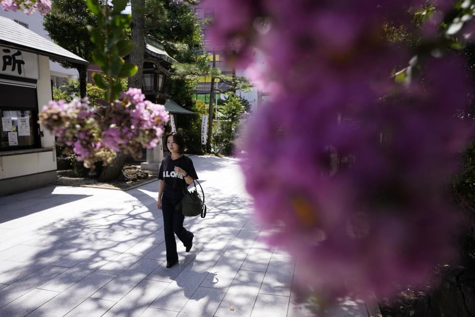 Momo Nomura, empresaraia y diseñadora gráfica, en su camino para recoger un Goshuin, un sello que certifica su visita al templo -- elaborado con una elegante caligrafía y dibujos de temporada -- en el santuario de Sakura Jingu, en Tokio, el 30 de agosto de 2023. (AP Foto/Eugene Hoshiko)
