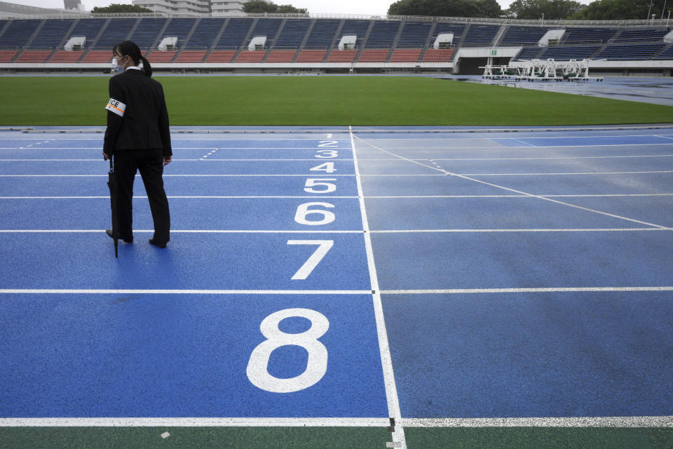 A police officer stands at empty race track after the unveiling ceremony for Olympic Flame of the Tokyo 2020 Olympic torch relay at Komazawa Olympic Park, which was initially built for the 1964 Tokyo Olympic Games, Friday, July 9, 2021, in Tokyo. (AP Photo/Eugene Hoshiko)