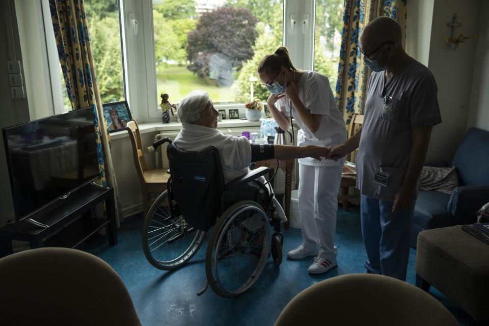 FILE - In this Thursday, July 9, 2020 file photo, nurse Jean-Claude Feda, right, and trainee Lyson Rousseau, center, both wearing face masks, to protect against the spread of coronavirus, measure the blood pressure of resident Odette Defraigne-Schmit at CHC Liege Mativa home for elderly people in Liege, BelgiumAuthorities in Belgium fear another deadly wave of coronavirus cases could soon hit care homes as the country confronts the risk of seeing its hospitals overwhelmed by COVID-19 patients, leading them to restrict nursing home visits. (AP Photo/Francisco Seco, File)