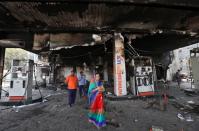 People stand at a damaged fuel station after it was set on fire by a mob in a riot affected area after clashes erupted between people demonstrating for and against a new citizenship law in New Delhi