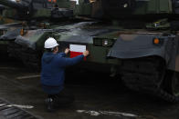 A worker puts a Polish flag on the South Korean Black Panther K2 tank in the Polish Navy port of Gdynia, Poland, Tuesday, Dec. 6, 2022. Poland's President Andrzej Duda and the defense minister on Tuesday welcomed the first delivery of tanks and howitzers from South Korea, hailing the swift implementation of a deal signed in the summer in the face of the war in neighbouring Ukraine. (AP Photo/Michal Dyjuk)