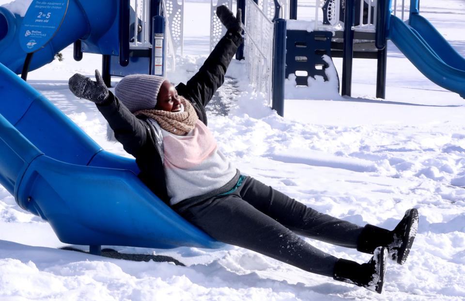 Esther Konchella, who is visiting her sister from Kenya, enjoys the snow as she slides down a slide at Barfield Park on Tuesday, Jan. 16, 2024. Show remains on the ground after snow started falling on Sunday and continued through Monday afternoon.