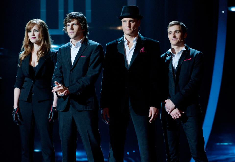 Isla Fisher, Jesse Eisenberg, Woody Harrelson, and Dave Franco stand on a stage