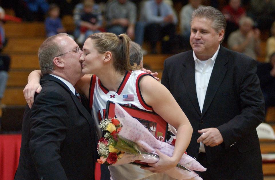 Marist College’s Maureen Magarity, center, gets a kiss from Marist College Women's basketball head coach Brian Giorgis, left, on Feb. 26, 2004, during a ceremony honoring the senior members of the team before the last home game of the season against Siena College at the McCann Center in the Town of Poughkeepsie. At right is Dave Magarity, Maureen's father and the then head coach of the Marist College men's basketball team.