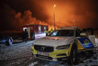 The police vehicle is parked at the entrance of the road to Grindavík with the eruption in the background, near Grindavik on Iceland's Reykjanes Peninsula, Monday, Dec. 18, 2023. A volcanic eruption started Monday night on Iceland's Reykjanes Peninsula, turning the sky orange and prompting the country's civil defense to be on high alert. (AP Photo/Marco Di Marco)