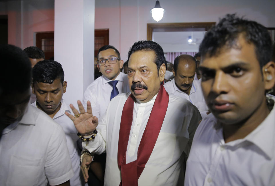 Newly appointed Sri Lankan Prime Minister Mahinda Rajapaksa, center, leaves a Buddhist temple after meeting his supporters in Colombo, Sri Lanka, Friday, Oct. 26, 2018. Sri Lankan President Maithripala Sirisena has sacked the country's prime minister and replaced him with a former strongman, state television said Friday. (AP Photo/Eranga Jayawardena)