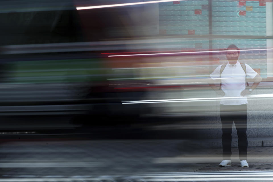 A car passes by a man wearing a protective mask standing in front of an electronic stock board showing Japan's Nikkei 225 index at a securities firm Wednesday, Sept. 29, 2021, in Tokyo. Asian shares fell sharply on Wednesday after a broad slide on Wall Street as investors reacted to a surge in U.S. government bond yields. (AP Photo/Eugene Hoshiko)