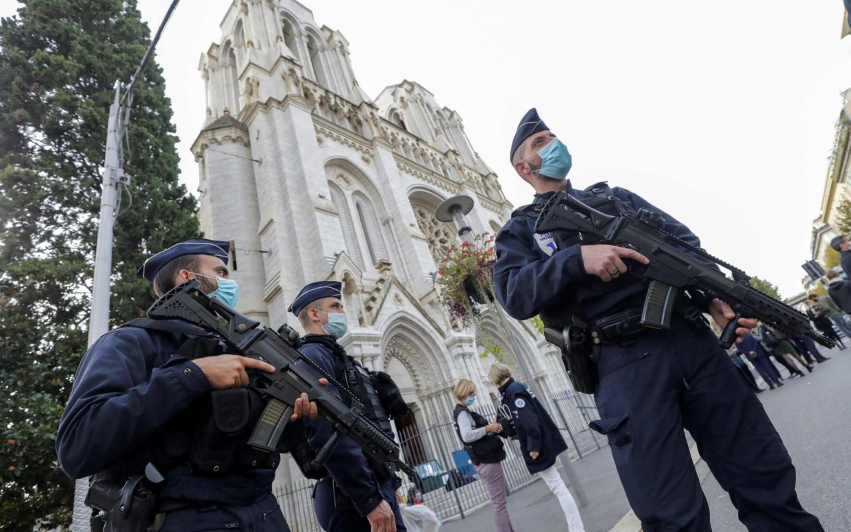 Police officers stand guard by the Notre-Dame Basilica in Nice  - AFP