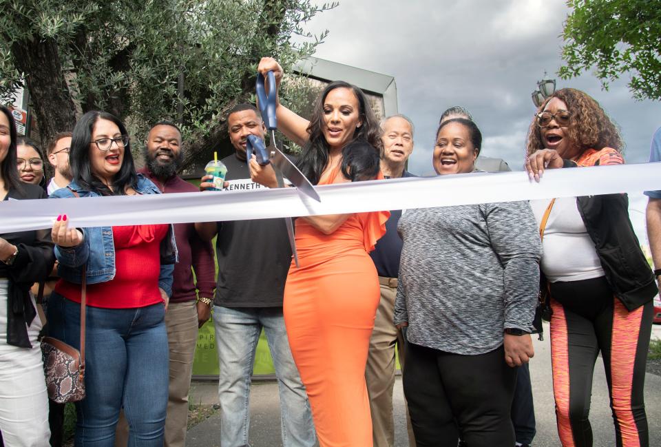 Lakeisha Little-Shaw, center, owner of the Shaw Bar, wields large scissors during a ribbon cutting ceremony for her new business, the F.I.T. Me gym, at the Waterfront Warehouse in downtown Stockton on Apr. 24, 2024.