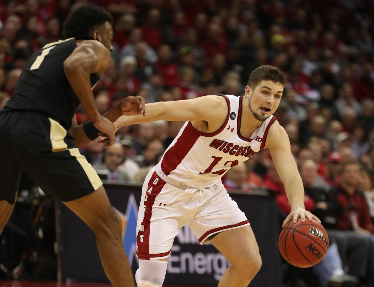 Feb 18, 2020; Madison, Wisconsin, USA; Wisconsin Badgers guard Trevor Anderson (12) dribbles the ball past Purdue Boilermakers forward Aaron Wheeler (left) at the Kohl Center. Mandatory Credit: Mary Langenfeld-USA TODAY Sports