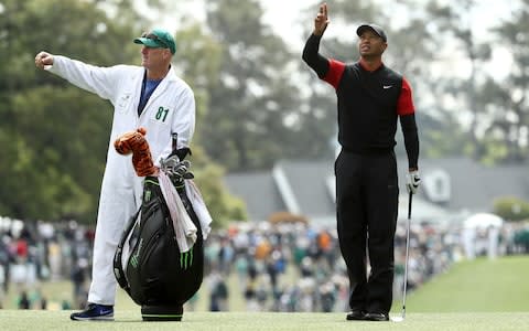 Tiger Woods of the United States waits on the first fairway with caddie Joe LaCava - Credit: Getty