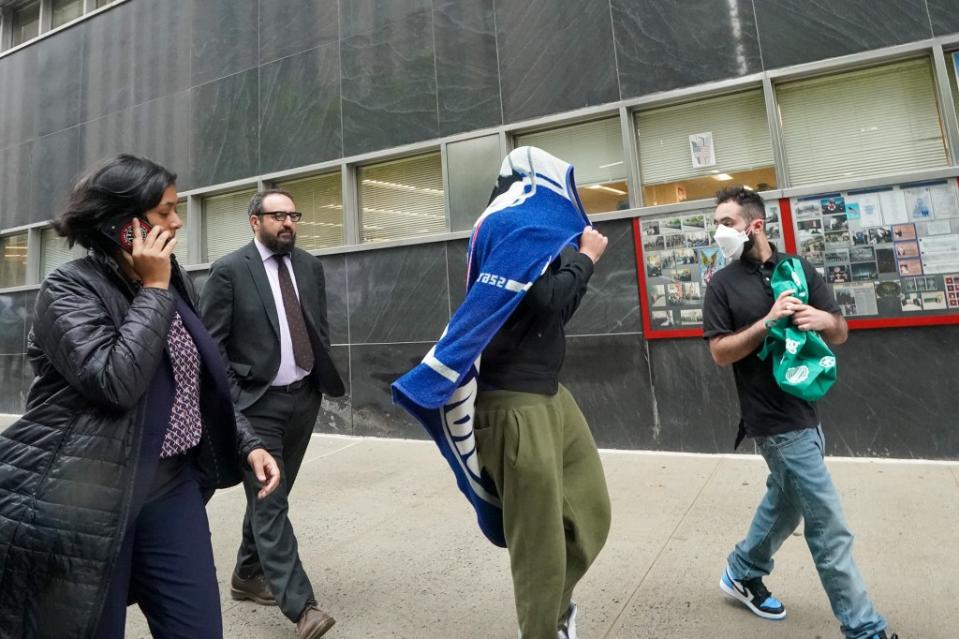 The teen suspect covers his head with a towel outside court Friday. Robert Miller