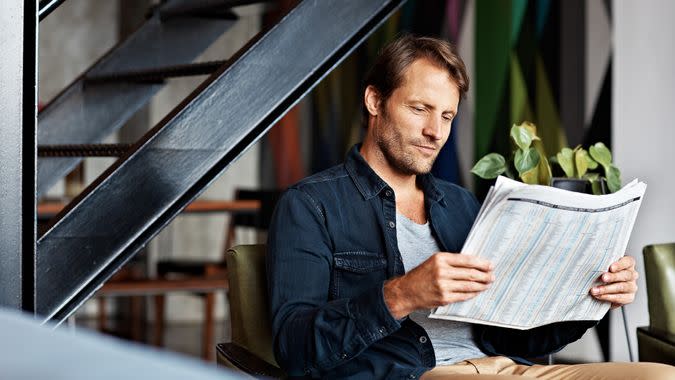 Shot of a mature man sitting in his living room reading a newspaper.