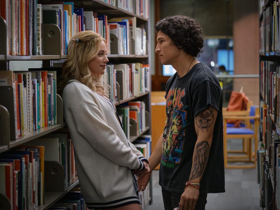 natalie and gabe standing in the stacks of a college library in look booth ways