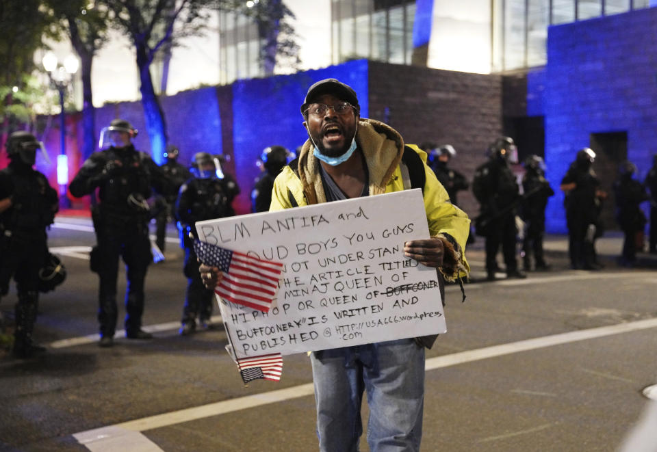 A protester holds a sign while rallying at the Mark O. Hatfield United States Courthouse on Saturday, Sept. 26, 2020, in Portland, Ore. (AP Photo/Allison Dinner)