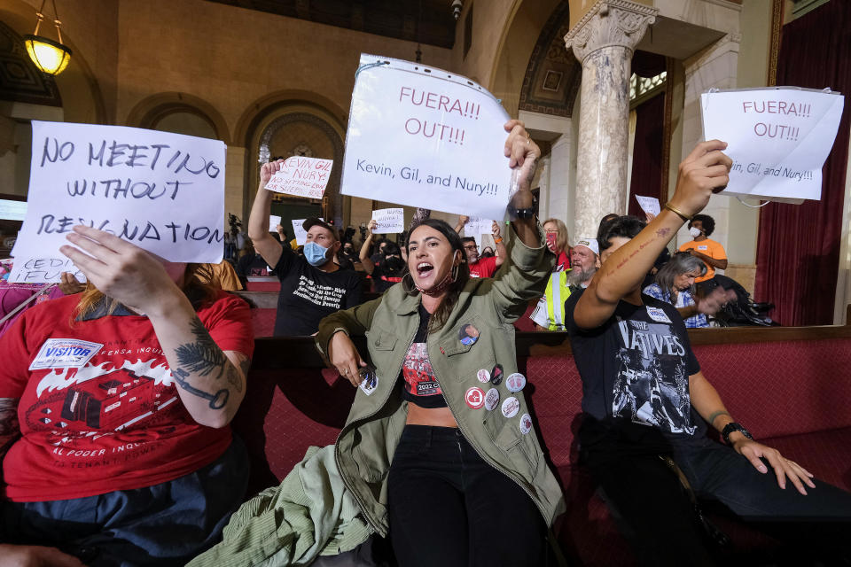 FILE - People hold signs and shout slogans as they protest before the cancellation of the Los Angeles City Council meeting on Oct. 12, 2022 in Los Angeles. On Oct. 9, a leaked recording revealed City Council President Nury Martinez, labor leader Ron Herrera, Council members, Kevin de Leon and Gil Cedillo participating in a private meeting in which the Latino Democratic officials made crude, racist remarks and plotted to expand their political power at the expense of Black voters during a realignment of council district boundaries. (AP Photo/Ringo H.W. Chiu, File)