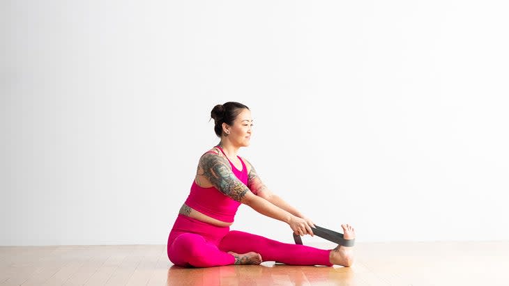 Woman demonstrating Head-to-Knee forward bend variation with strap