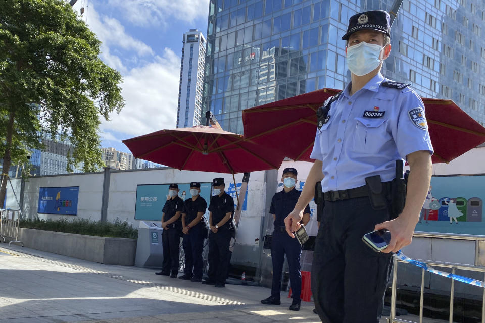 A police officer and security guards stand on duty outside the headquarters for Evergrande in Shenzhen in southern China, Thursday, Sept. 23, 2021. The Chinese real estate developer whose struggle to avoid defaulting on billions of dollars of debt has rattled global markets says it will pay interest due Thursday to bondholders in China but gave no sign of plans to pay on a separate bond abroad. (AP Photo/Ng Han Guan)