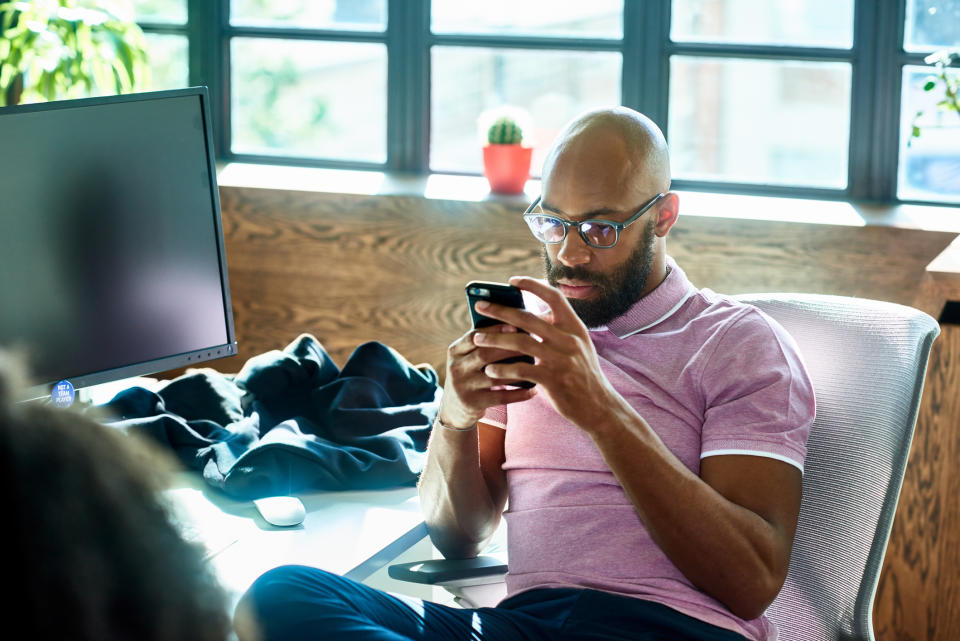 Person sitting at a table using a smartphone, with a blurred screen in the background