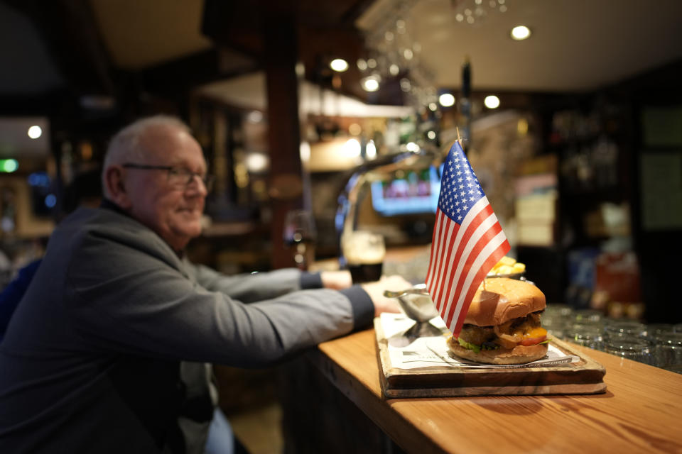 A customer in a bar in Carlingford, Ireland, Tuesday, April 11, 2023, looks at a food plater adorned with a US flag, as final preparations are made of President Joe Biden's visit to the town later in the week. President Biden is visiting Northern Ireland and Ireland to celebrate the 25th Anniversary of the Good Friday Agreement. (AP Photo/Christophe Ena)