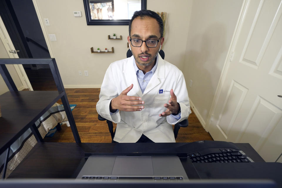 Medical director of Doctor on Demand Dr. Vibin Roy speaks to a patient during an online primary care visit from his home, Friday, April 23, 2021, in Keller, Texas. Some U.S. employers and insurers want you to make telemedicine your first choice for most doctor visits. Retail giant Amazon and several insurers have started or expanded virtual-first care plans to get people thinking telemedicine routinely, even for annual checkups. (AP Photo/LM Otero)