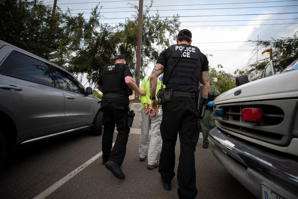 Two U.S. Immigration and Customs Enforcement (ICE) officers walk with a handcuffed man in Escondido, Calif., July 8, 2019