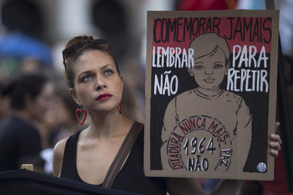 A woman holds a sign that reads in Portuguese "Never commemorate, remember to not repeat. Dictatorship never more," during a protest against the military coup of 1964 in Rio de Janeiro, Brazil, Sunday, March 31, 2019. Brazil's president Jair Bolsonaro, a former army captain who waxes nostalgic for the 1964-1985 dictatorship, asked Brazil's Defense Ministry to organize "due commemorations" on March 31, the day historians say marks the coup that began the dictatorship. (AP Photo/Leo Correa)