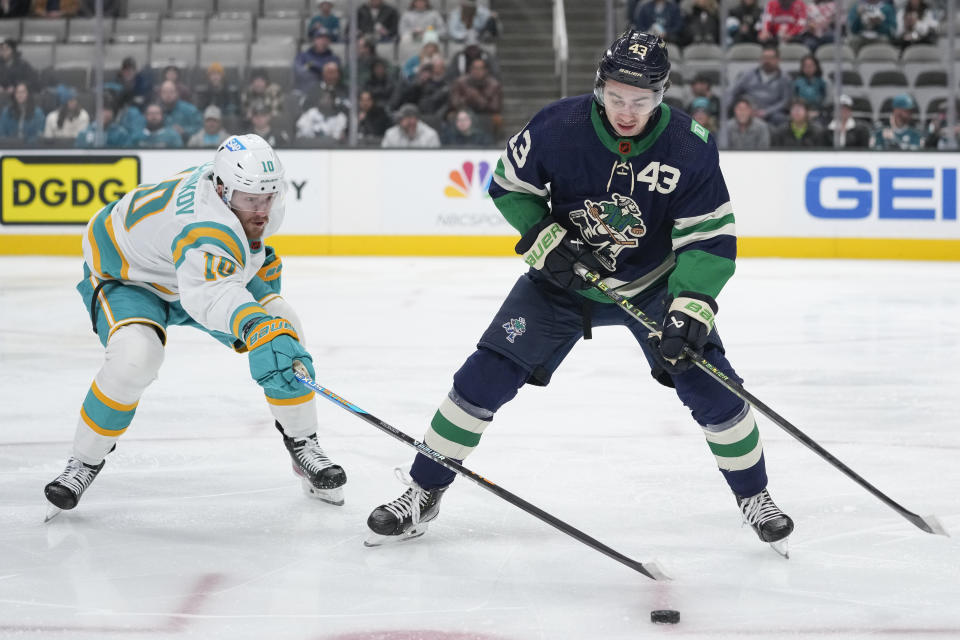 San Jose Sharks left wing Evgeny Svechnikov, left, and Vancouver Canucks defenseman Quinn Hughes chase the puck during the first period of an NHL hockey game in San Jose, Calif., Wednesday, Dec. 7, 2022. (AP Photo/Godofredo A. Vásquez)