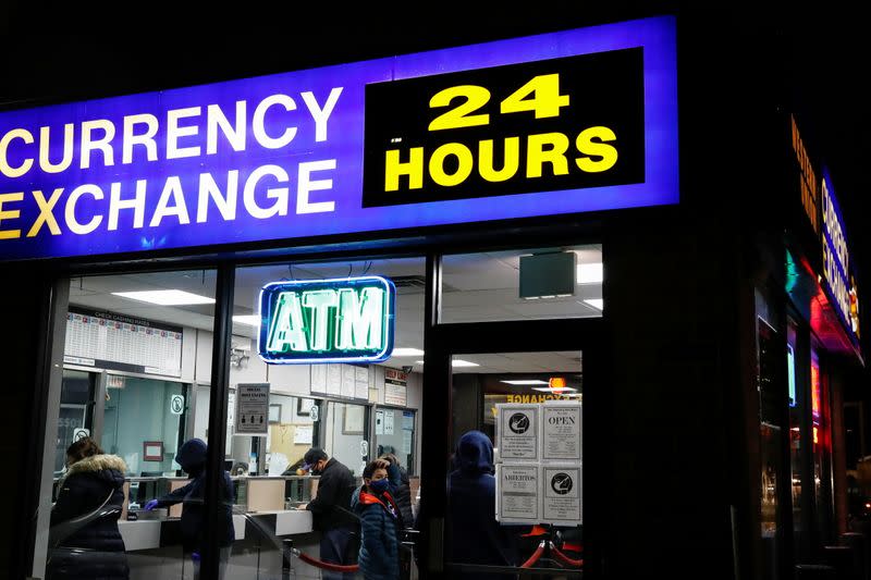 People wait in line wearing protective face masks, as the global outbreak of the coronavirus disease (COVID-19) continues, at a Western Union money transfer and currency exchange facility in Chicago, Illinois