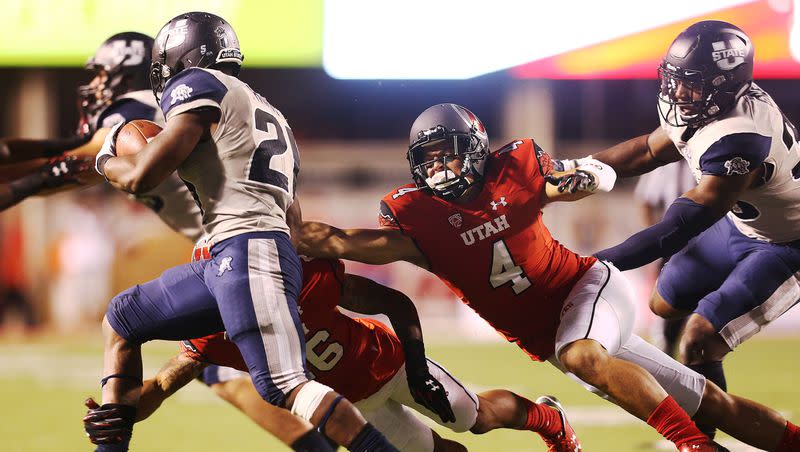 Utah defenders attempt to tackle Utah State’s LaJuan Hunt at Rice-Eccles Stadium in Salt Lake City. The two programs announced Thursday that they have agreed to a three-year series that will begin in 2024.