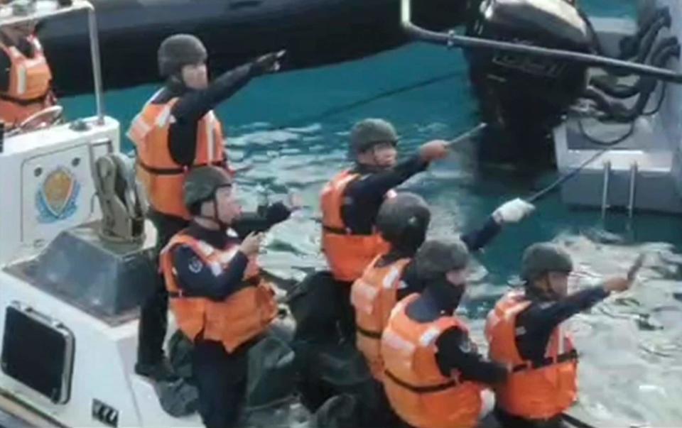 Chinese coastguards hold knives and machetes as they approach Philippine troops on Monday