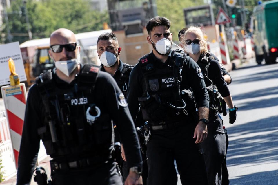 Polizisten mit Mund-Nasen-Schutz gehen vor Beginn der Demonstration gegen die Corona-Maßnahmen über den Boulevard Unter den Linden.<span class="copyright">Paul Zinken / dpa</span>