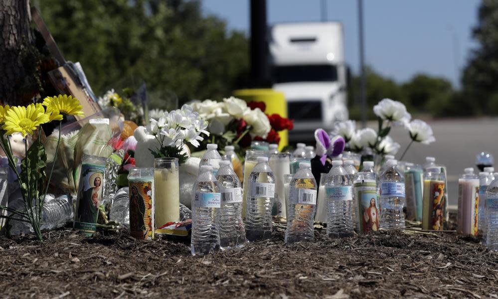 Flowers, candles and bottles of water help create a makeshift memorial near the site where authorities discovered a tractor-trailer packed with people in San Antonio.
