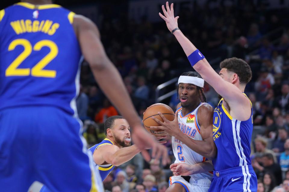 Oklahoma City Thunder guard Shai Gilgeous-Alexander (2) goes between Golden State Warriors guard Klay Thompson (11) and guard Stephen Curry (30) during an NBA basketball game between the Oklahoma City Thunder and the Golden State Warriors at Paycom Center in Oklahoma City, Monday, Jan. 30, 2023. 