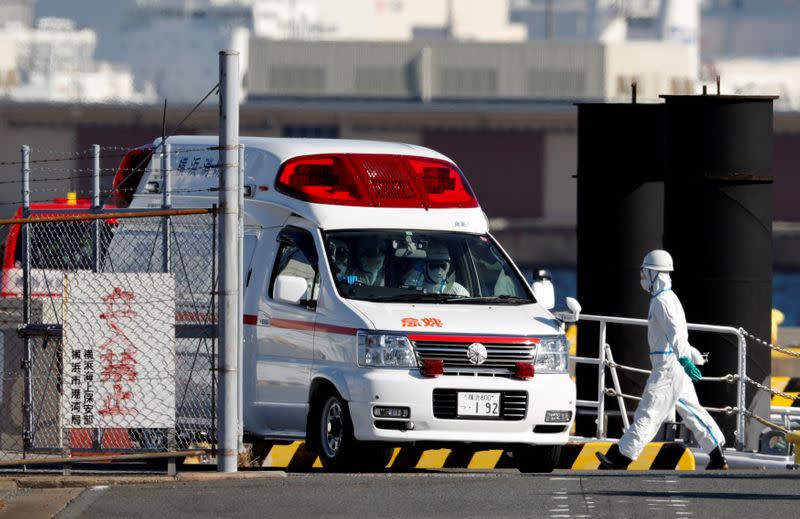 Ambulance workers in protective gear drive an ambulance which is believed to carry a person who was transferred from cruise ship Diamond Princess after ten people tested positive for coronavirus, at a maritime police's base in Yokohama