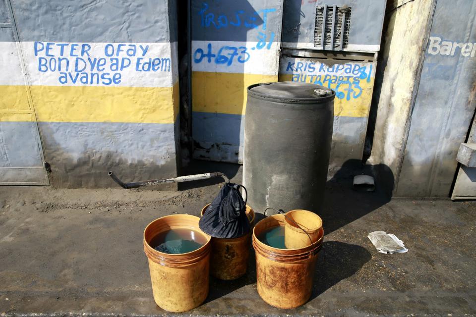 In this April 16, 2019 photo, open containers full with fuel stand on the sidewalk to be sold near the Thor terminal in Carrefour, a district of Port-au-Prince, Haiti. As Venezuelan President Nicolás Maduro's government has struggled with plunging petroleum production and a cratering economy, the South American country has been forced to stop sending billions in subsidized oil to countries throughout Central America and the Caribbean, including Haiti. (AP Photo/Dieu Nalio Chery)