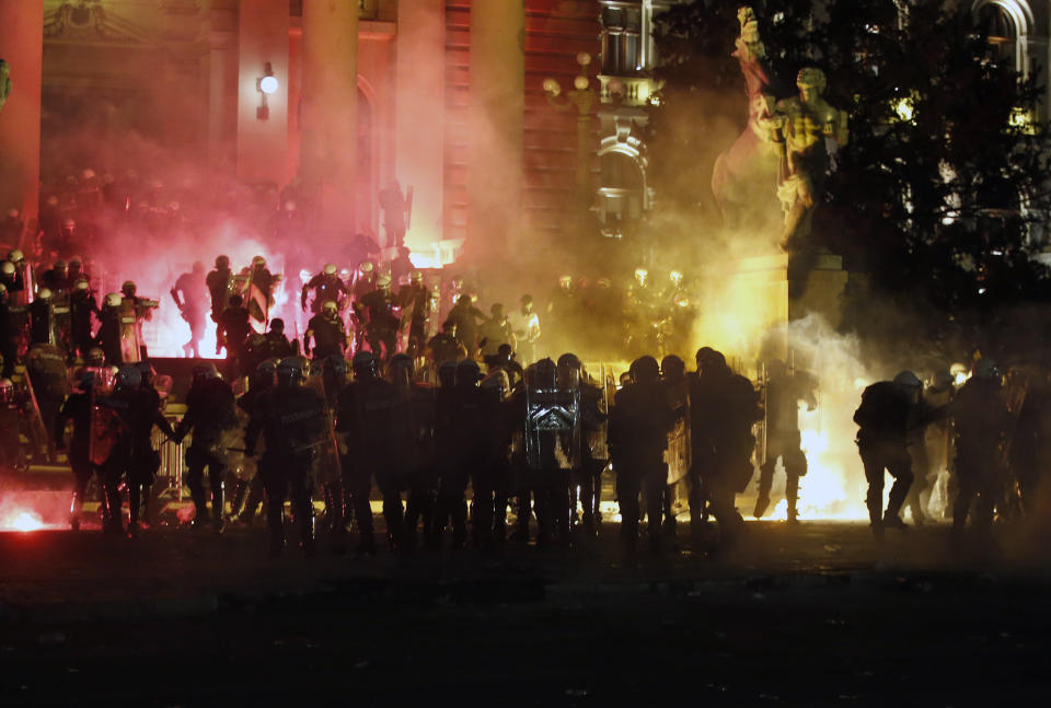 Protesters clash with riot police on the steps of the Serbian parliament during a protest in Belgrade, Serbia, Friday, July 10 2020. Hundreds of demonstrators tried to storm Serbia's parliament on Friday, clashing with police who fired tear gas during the fourth night of protests against the president's increasingly authoritarian rule. The protests started on Tuesday when President Aleksandar Vucic announced that Belgrade would be placed under a new three-day lockdown following a second wave of confirmed coronavirus infections. (AP Photo/Darko Vojinovic)