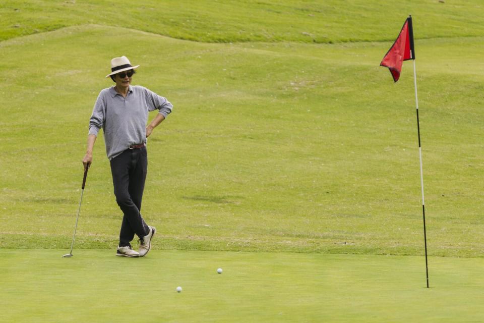 A golfer stands at the 18th hole at the Wilson Golf Course while leaning on a golf club.