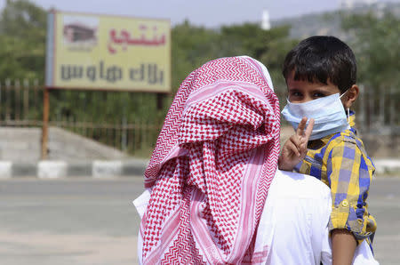 A boy wearing a mask is held by his father in Taif June 7, 2014. REUTERS/Mohamed Alhwaity