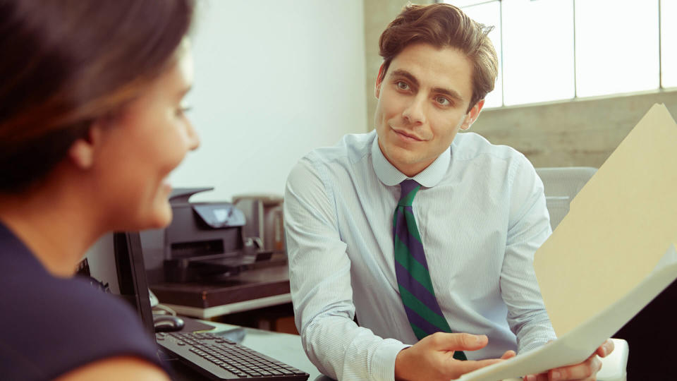 Young male professional shows documents to woman in meeting.